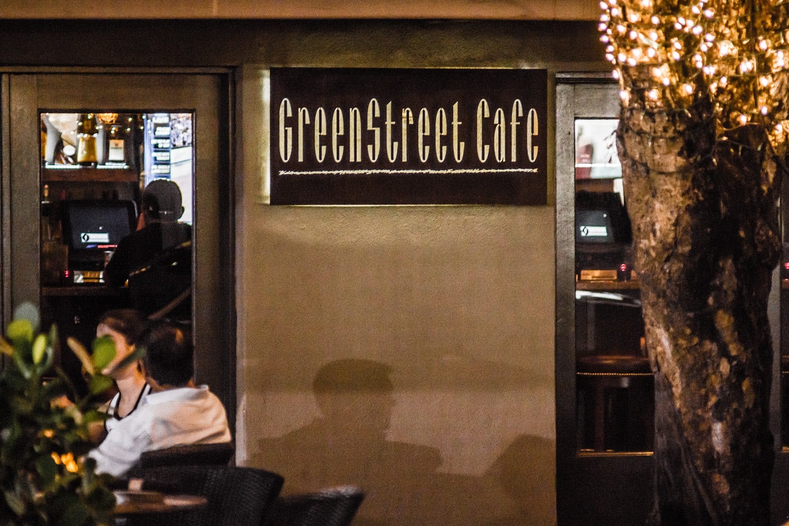 The GreenStreet Cafe sign and sidewalk tables lit at night on Commodore Plaza in Coconut Grove