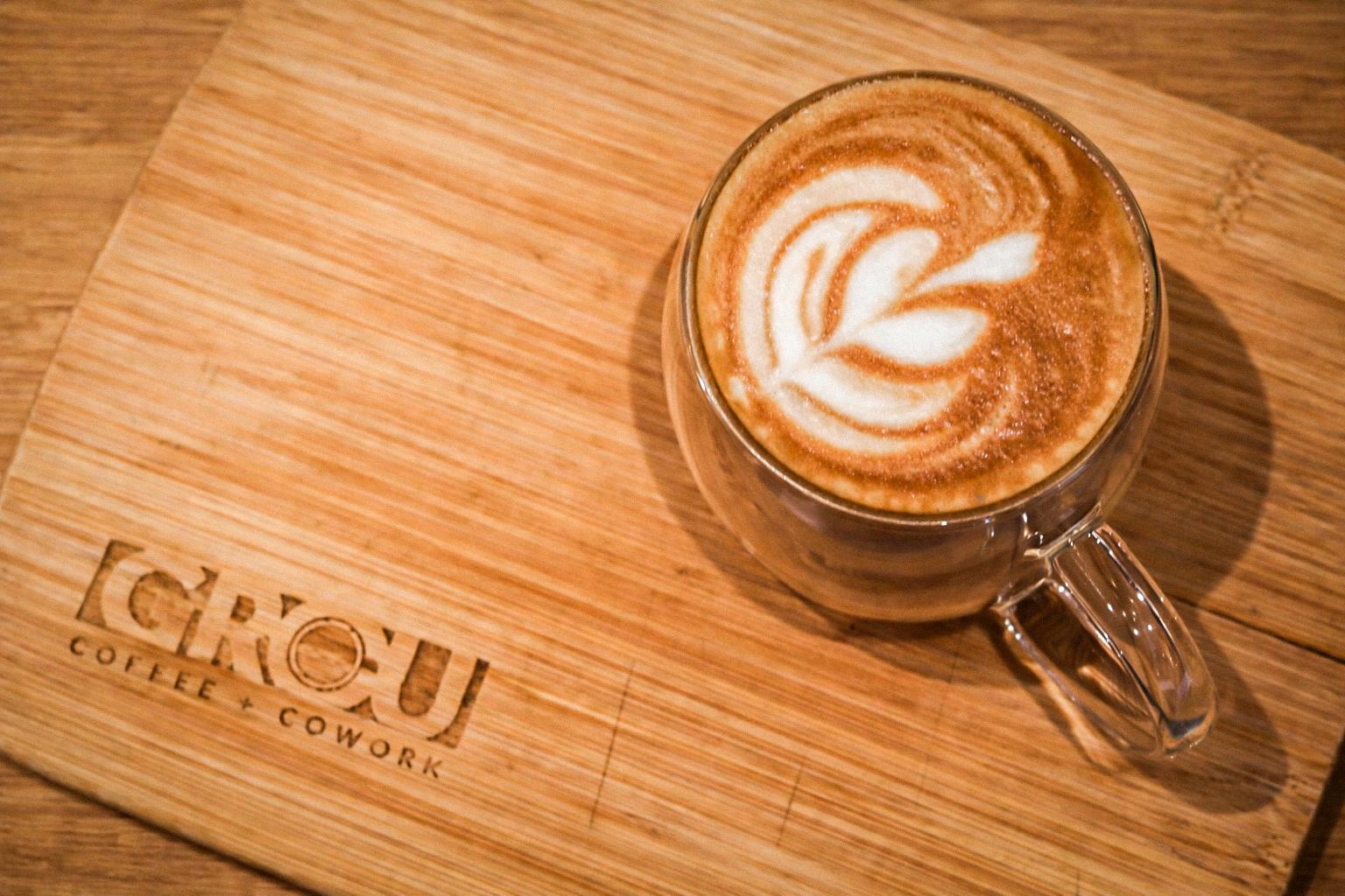 Flat white with rosetta latte art in a glass mug on a GROU bamboo board